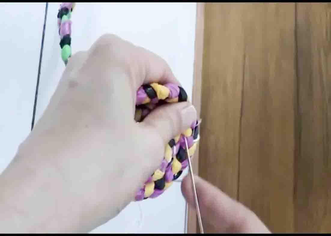 Stitching the braided plastic while rounding it into a rug