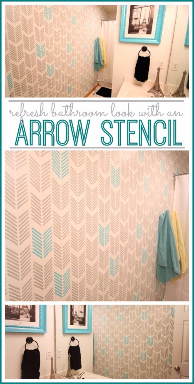 Small bathroom wall stencilled floor to ceiling with gray arrows and scattered turquoise arrows beside a framed print