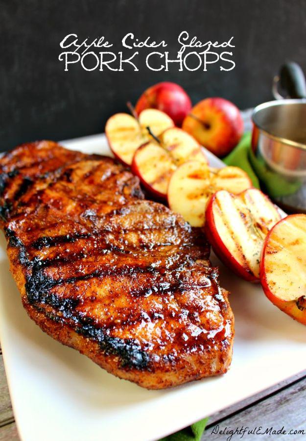 Apple cider glazed chops with dark grill marks on a white platter beside caramelized grilled apple slices