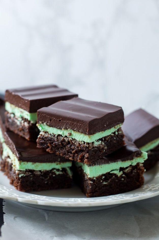 Mint brownies with a pale green buttercream layer and a smooth dark chocolate ganache top on a plate
