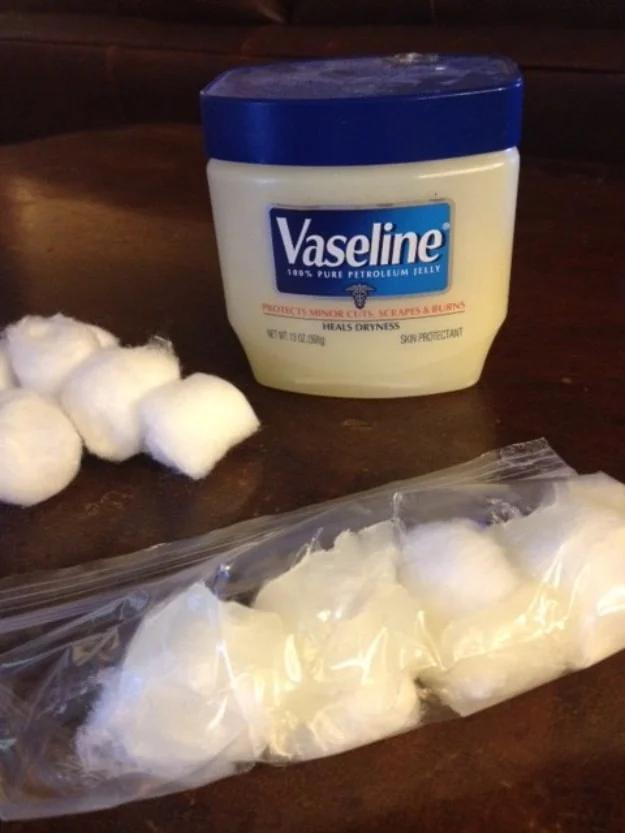 Jar of Vaseline beside loose cotton balls and a sandwich bag of petroleum jelly coated fire starters