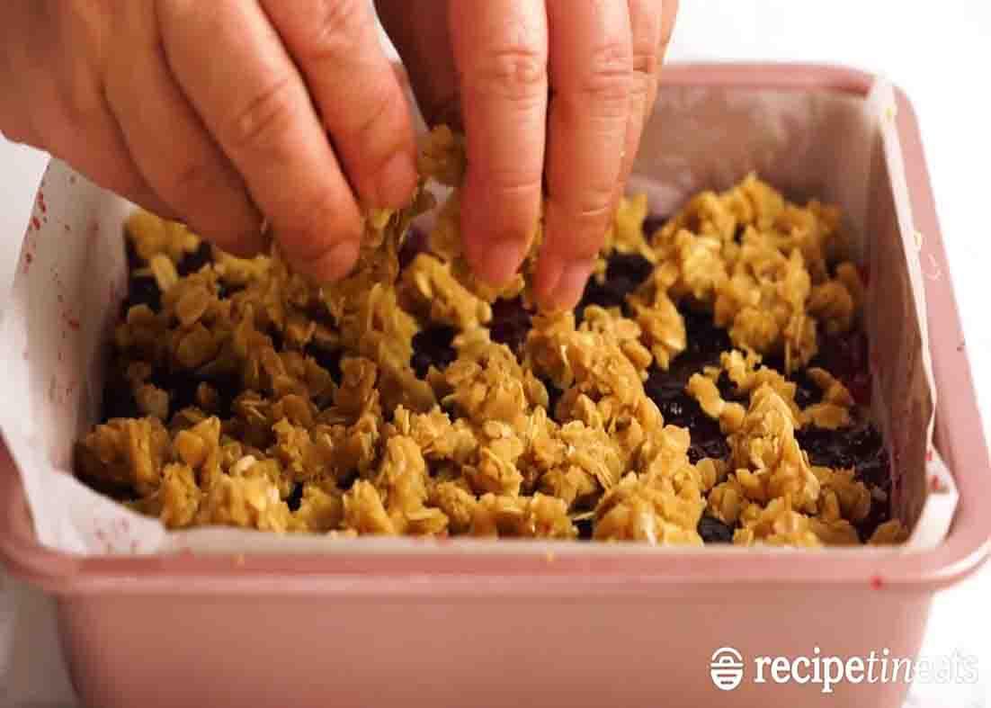Topping the raspberry jam oat bars with crumbles