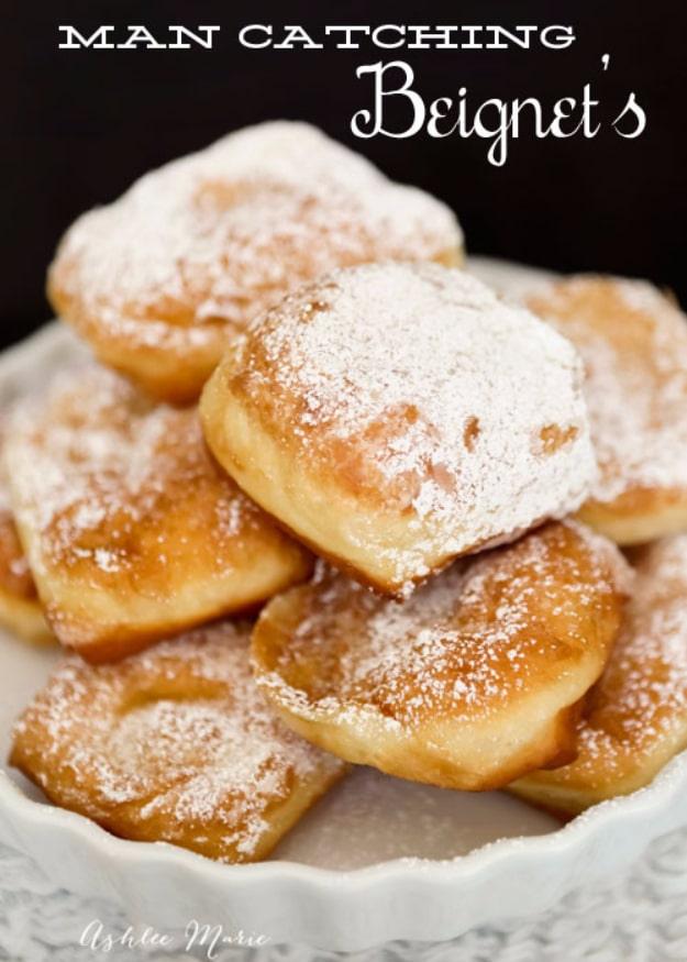 New Orleans beignets, square fried dough pillows buried under a heavy dusting of powdered sugar on a plate