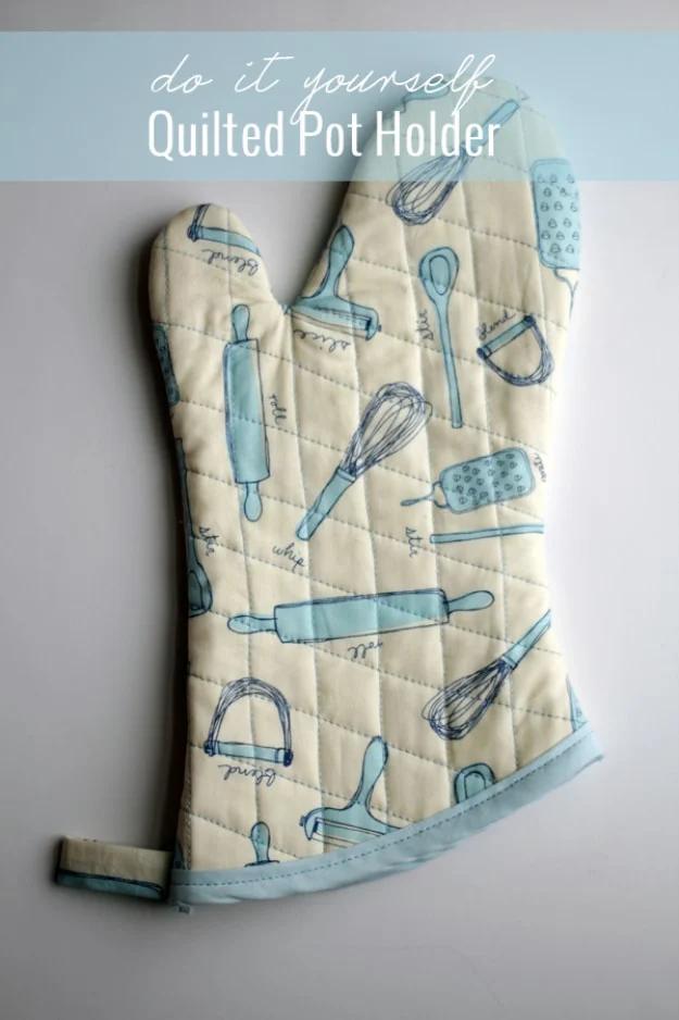 Quilted oven mitt printed with blue kitchen utensils hanging against a pale wall, shown below a title band