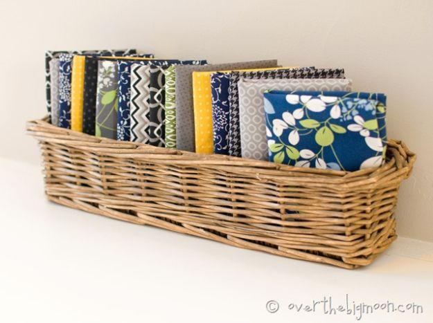 Fat quarter dinner napkins in navy, green, gray and yellow prints, folded and standing on edge in a wicker basket