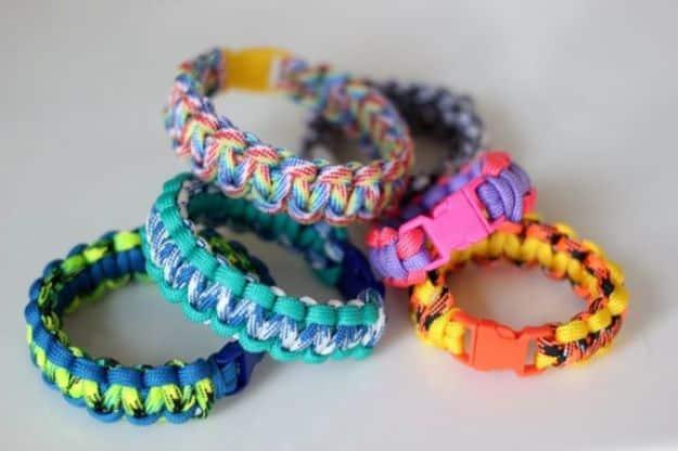 Pile of bright kids paracord bracelets in blue, teal, pink and yellow with colorful plastic buckles and clips