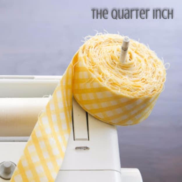 A roll of yellow gingham quilt binding sitting on the vertical spool holder of a white sewing machine