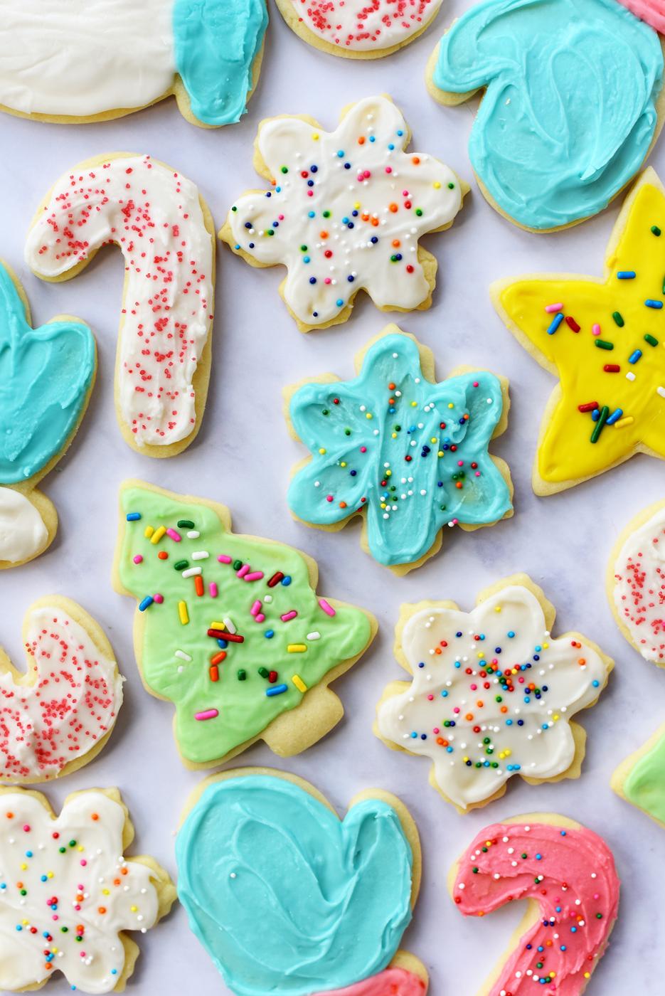 Soft iced sugar cookies shaped like trees, stars, mittens and candy canes in white, aqua, pink and yellow with sprinkles