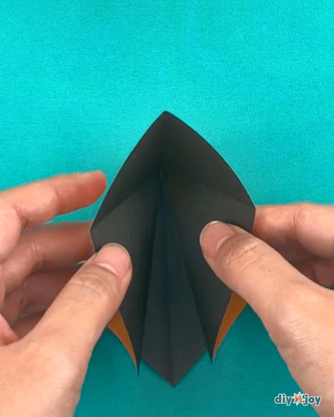 Flower paper project shown mid fold, the paper lily being shaped for handmade party decorations and gifts