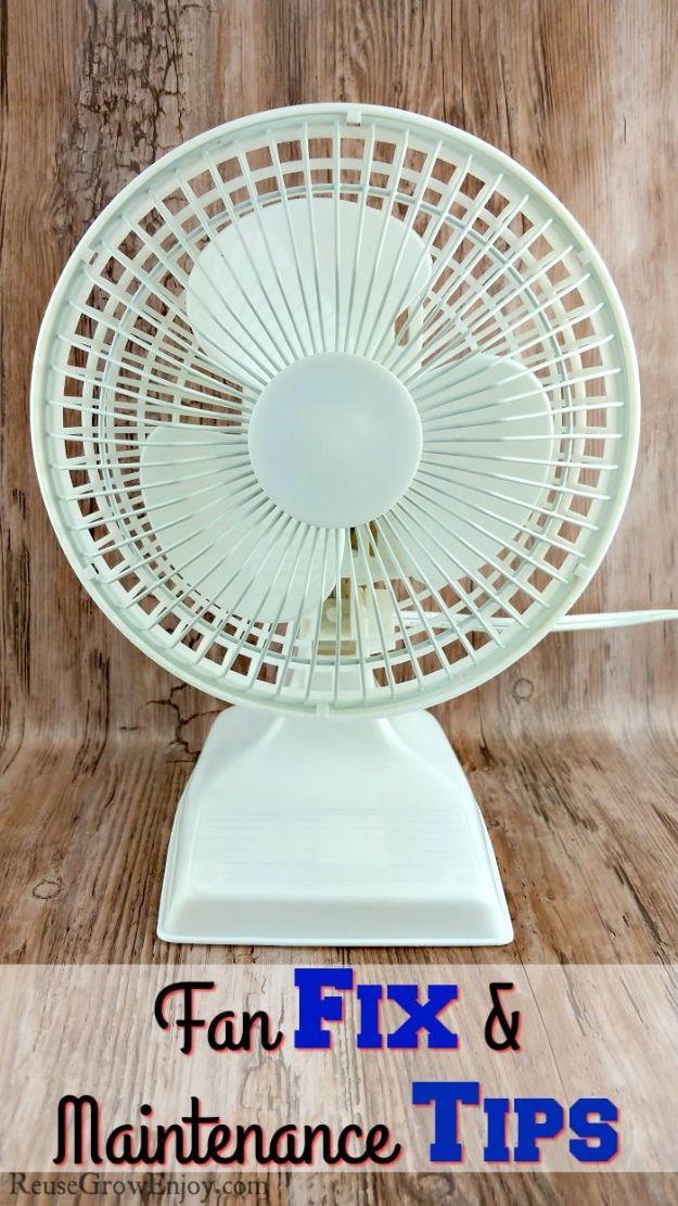 Repair fan, a white desk fan with a round guard and rectangular base standing against weathered brown wood boards
