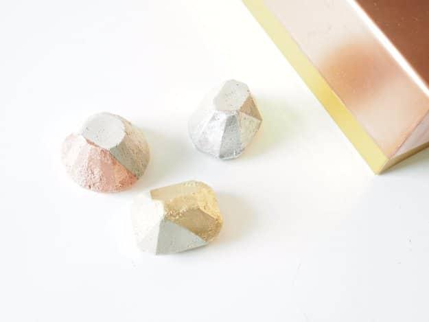 DIY concrete paper weights, three small faceted gray cement blocks with painted pink, silver and gold corners