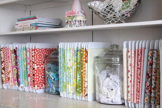 Shelf of fabric wrapped around white comb binding spines filed upright like books, glass jars of lace between sections