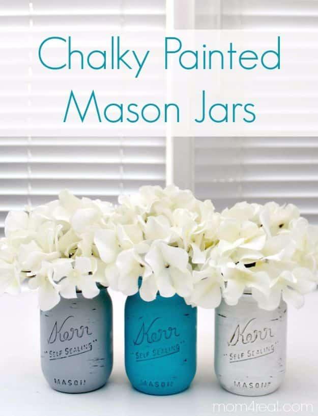 Pin graphic reading Chalky Painted Mason Jars showing teal, blue and gray jars holding white hydrangeas