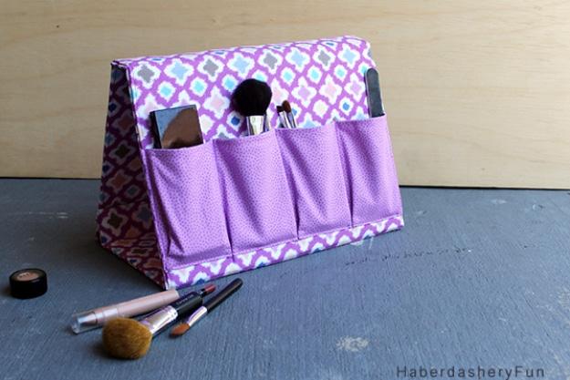 Purple and gray print A frame fabric organizer standing open on a wooden table with four pockets holding brushes