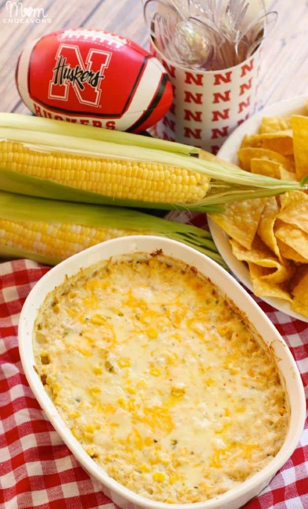 Hot corn dip baked in a dish with sweet corn kernels and green chiles under bubbling browned melted cheese