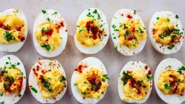 A tray of Oprah Winfrey deviled eggs topped with paprika and parsley, an easy celebrity party recipe
