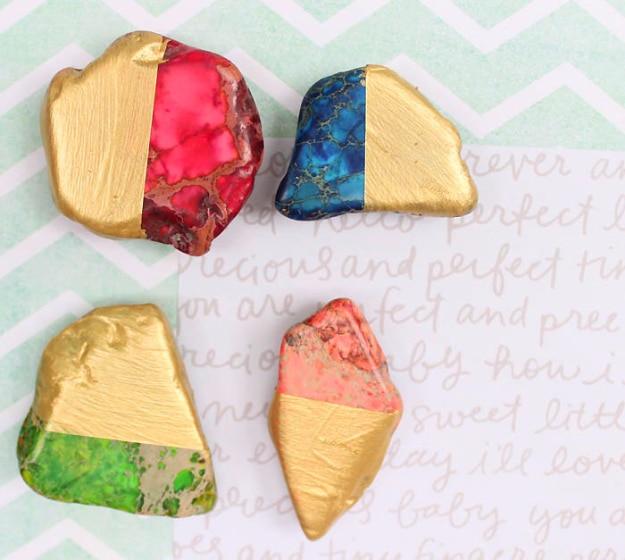 Six wooden shapes half dipped in gold paint stuck to a fridge door, holding up a card, handmade shop magnets