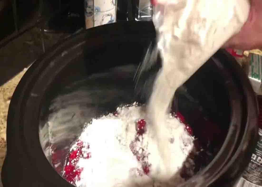 Adding the cake mix to the crock pot for the cherry cobbler