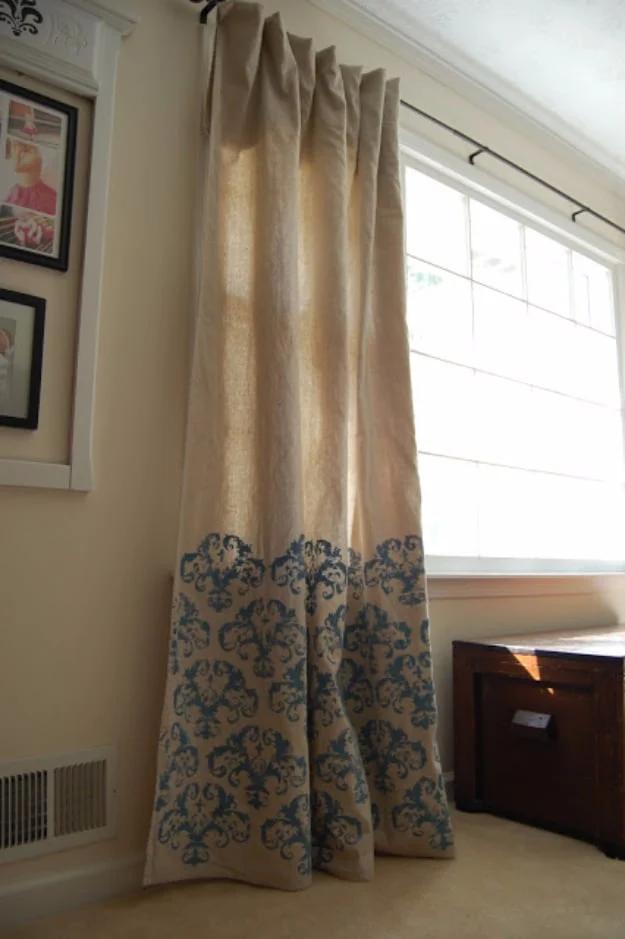 DIY curtain panel in natural drop cloth canvas with a blue stenciled damask border across the lower third