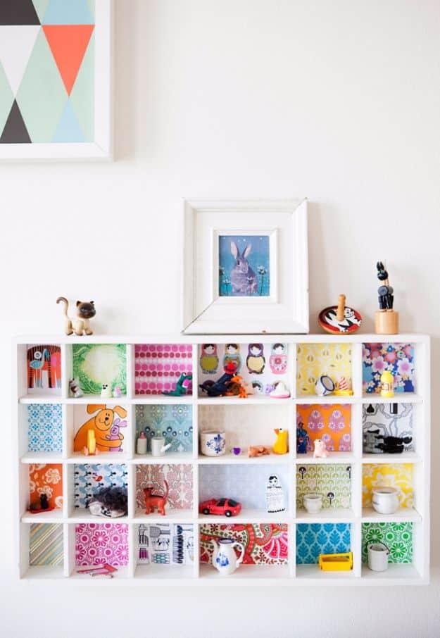 Wallpaper backed bookcase, a white grid shelf with each compartment backed in a different paper and holding small ornaments