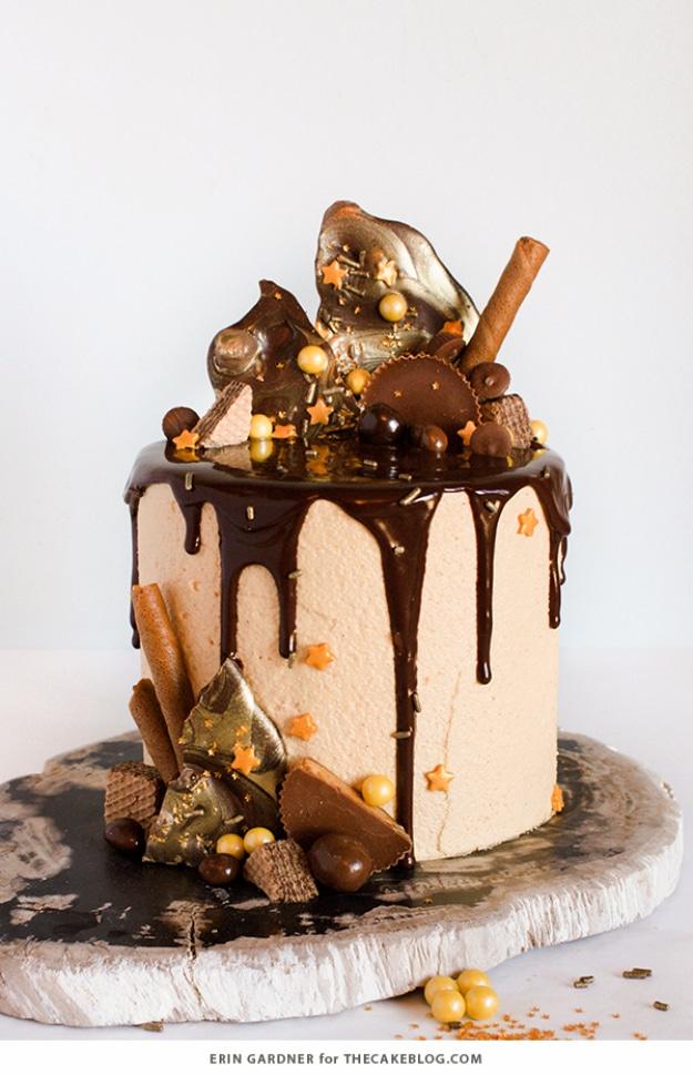 Tall birthday cake with dark chocolate ganache drips, candy bars and chocolate shards piled on the top
