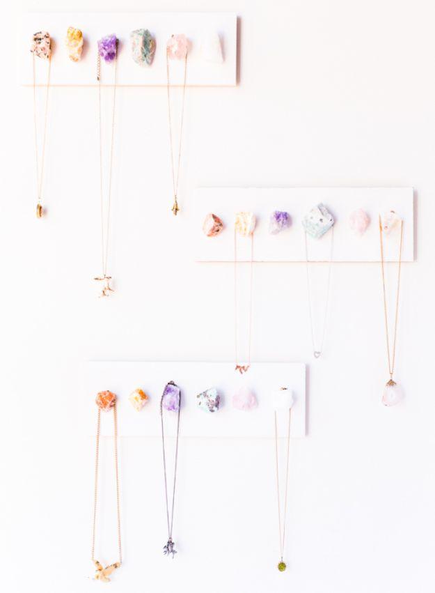 Rows of raw crystal points mounted on white wall plaques with gold chain necklaces hanging from them