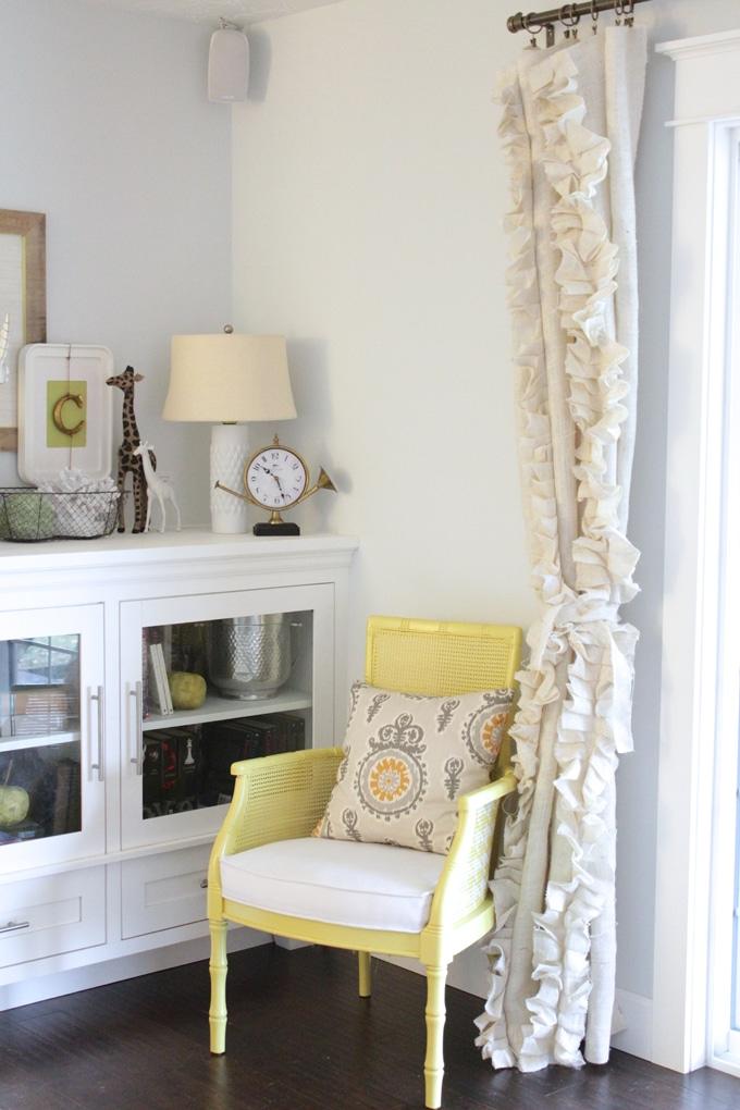 DIY curtain panel in cream burlap covered in vertical rows of hand pleated ruffles beside a white cabinet
