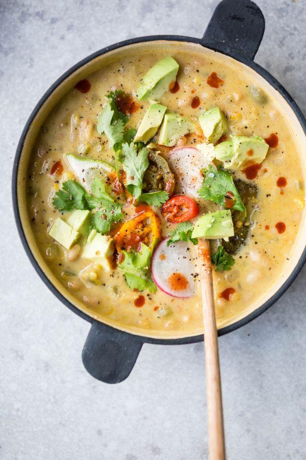 Creamy vegetarian white chili in a black rimmed pan with avocado, cilantro, radish and sliced chillies