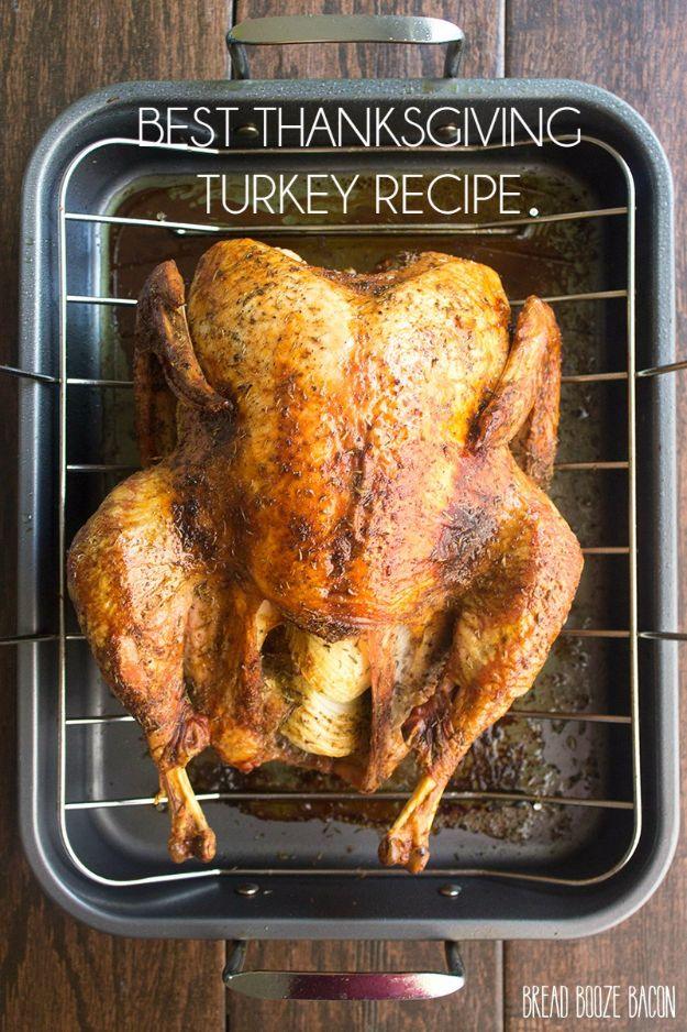 Herb roasted whole turkey with crisp golden skin, resting on a platter with halved onions and fresh herbs
