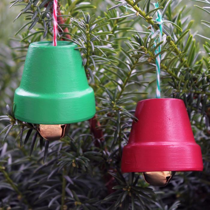 Mini terra cotta pots painted red and green, hung upside down as Christmas bells with jingle bells on baker's twine