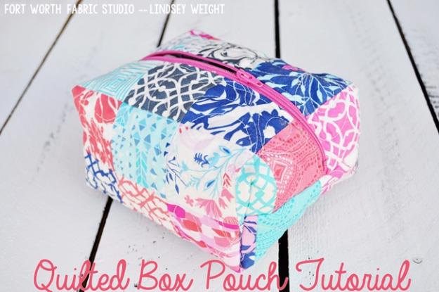A boxy quilted pouch standing upright on its own, the outer panel pieced from fabric scraps, long zipper open at the top
