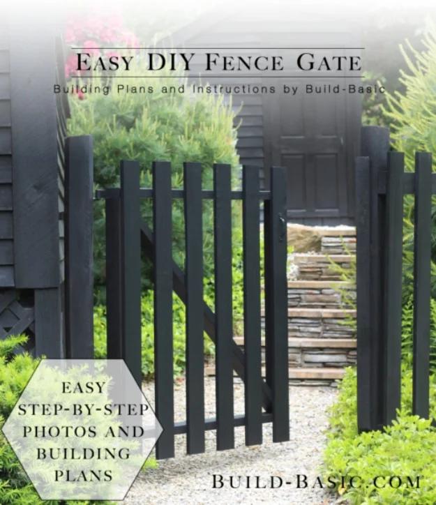Easy DIY fence gate, a dark gray picket gate with a wooden frame set between stone steps and green shrubs in a garden