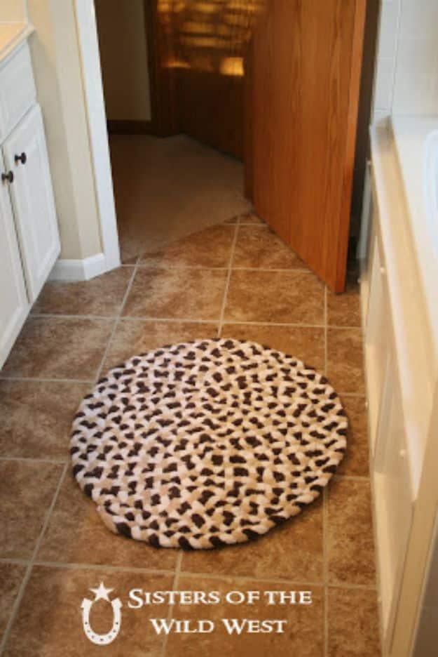 Round braided DIY rug in cream and dark brown made from old bath towels lying on tile in a bathroom doorway