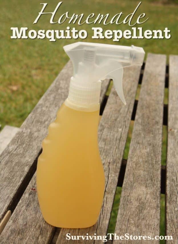 Spray bottle of homemade amber colored mosquito repellent sitting on a weathered wooden picnic table