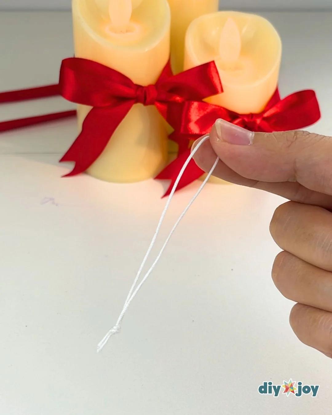Christmas Crafts - fingers holding a short length of white string knotted at one end