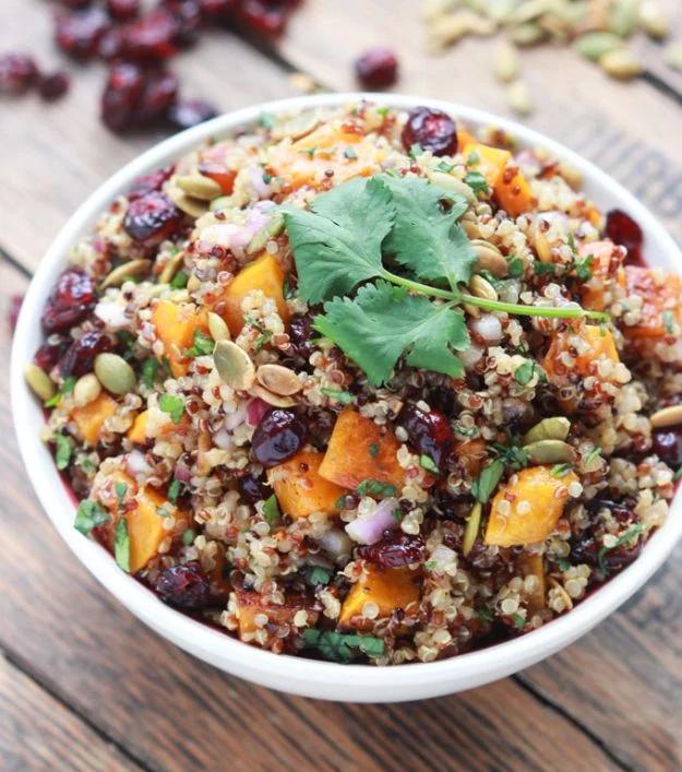 Butternut squash and cranberry quinoa salad in a white bowl with pumpkin seeds and dried cranberries