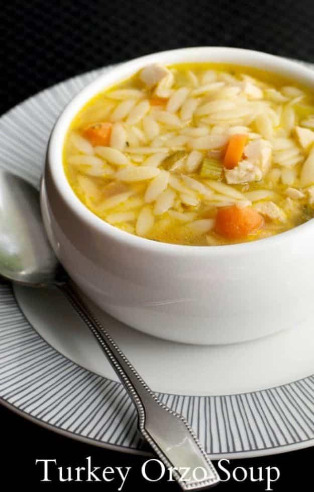 Turkey orzo soup in a white bowl with diced carrots, celery and small orzo pasta in a clear golden broth