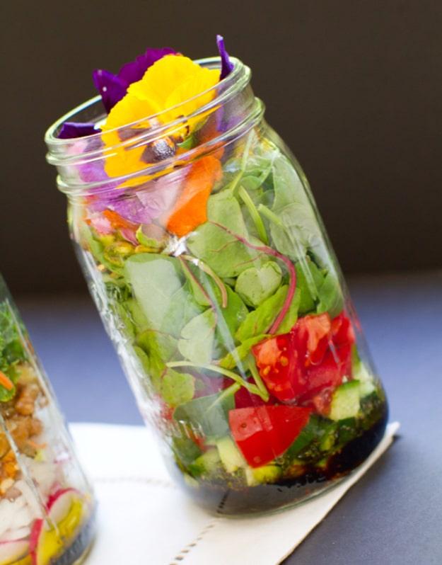 Vegan salad in a jar layered with dressing at the bottom, beans and chopped vegetables, and greens packed on top