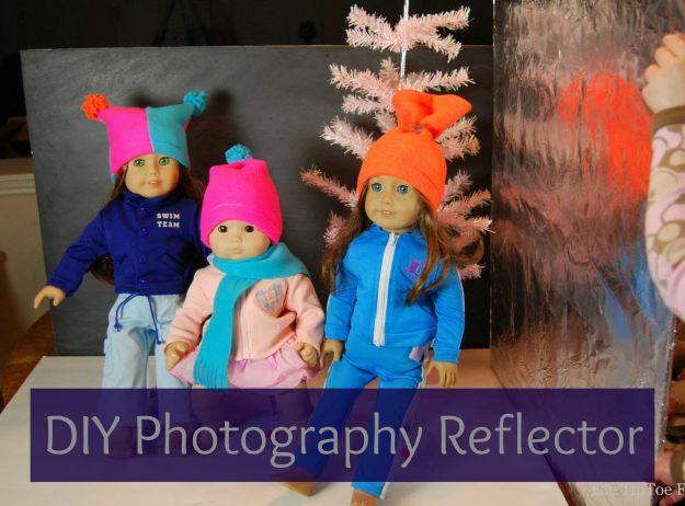 DIY photography reflector board, three dolls in knitted hats shot against a dark gray backdrop beside a pink paper tree
