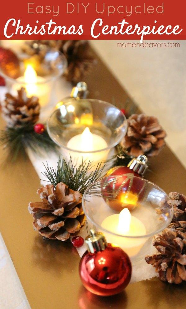 A gold painted wood tray of Epsom salt snow, glass votive candles, pinecone sprigs and red ornaments on a dining table
