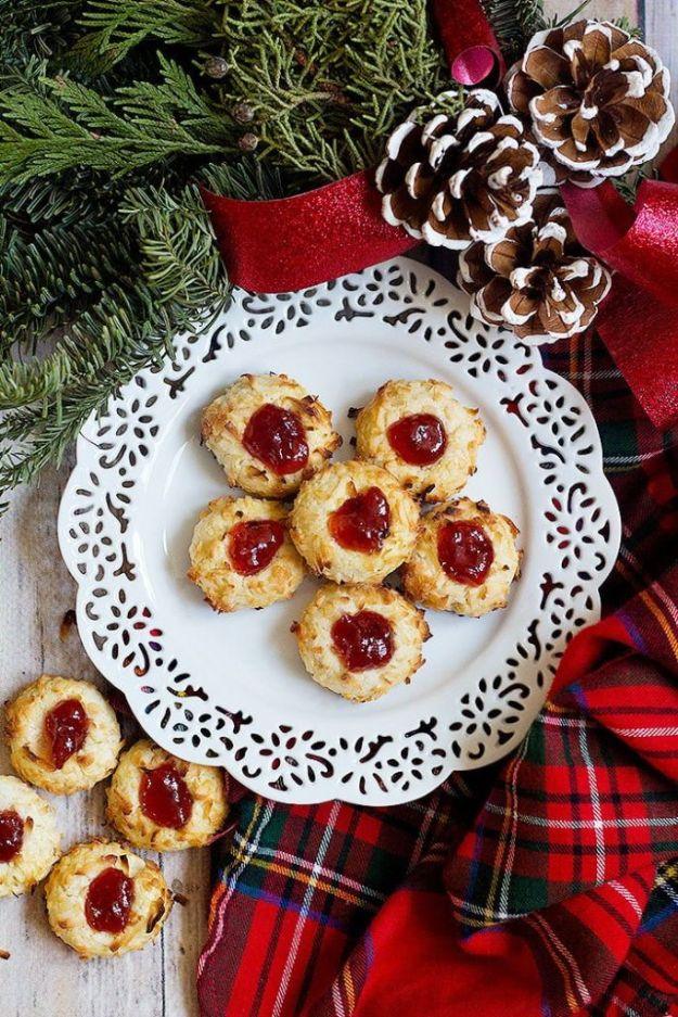 Coconut edged raspberry jam thumbprint cookies on a white doily plate with pine cones and a red plaid cloth