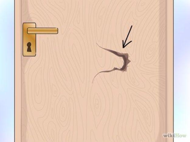 Illustration of a wooden door with a brass lever handle and a jagged hole punched through the panel beside it