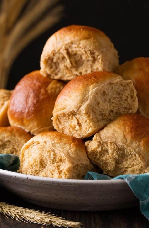 Honey whole wheat rolls baked golden brown in a pan and brushed with melted butter while they are warm