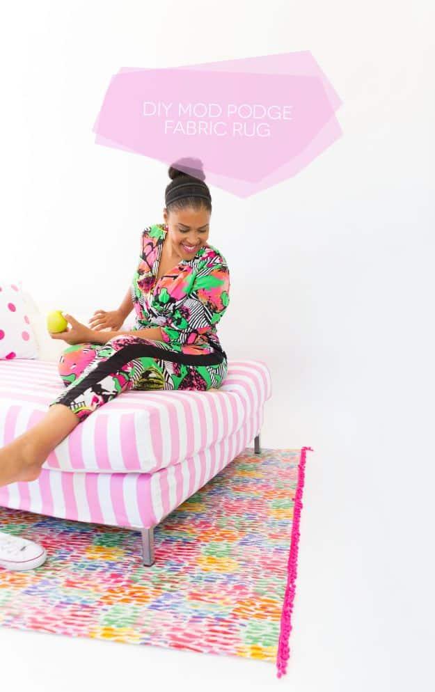 Bright multicoloured DIY fabric rug with hot pink pom pom trim under a striped bench in a white studio