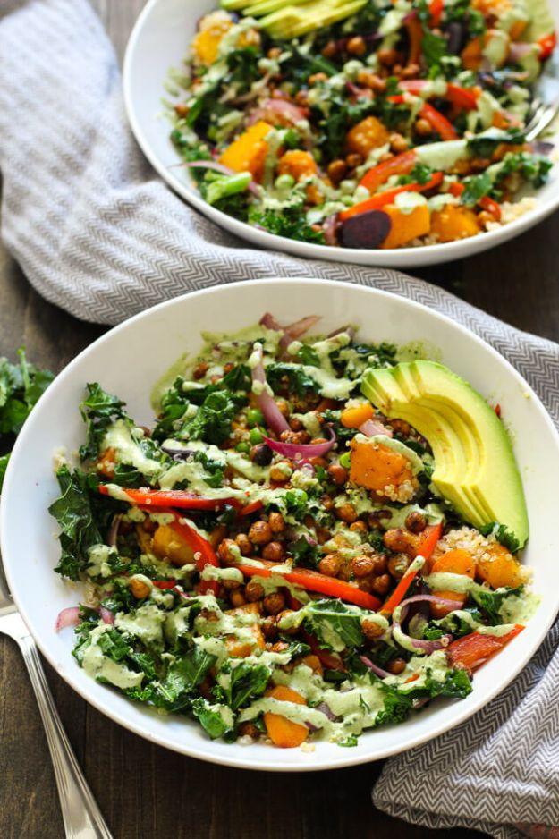 Warm kale and quinoa bowls with roasted chickpeas, butternut squash, avocado and red pepper in two white bowls