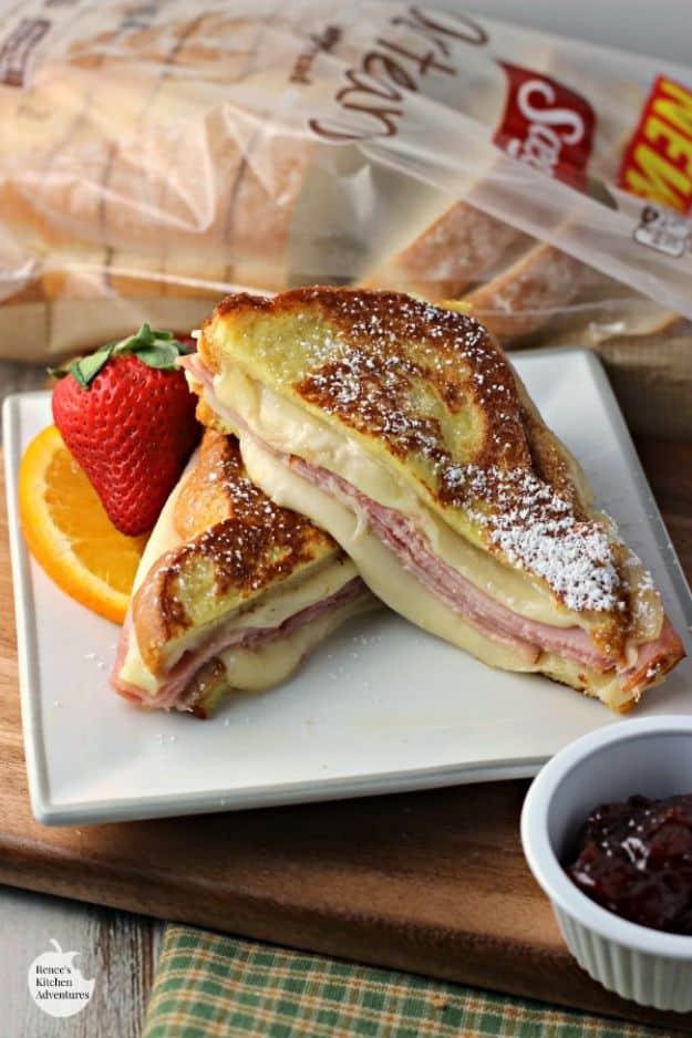 Monte Cristo style grilled cheese sandwich cut in half with melting Swiss, dusted with powdered sugar