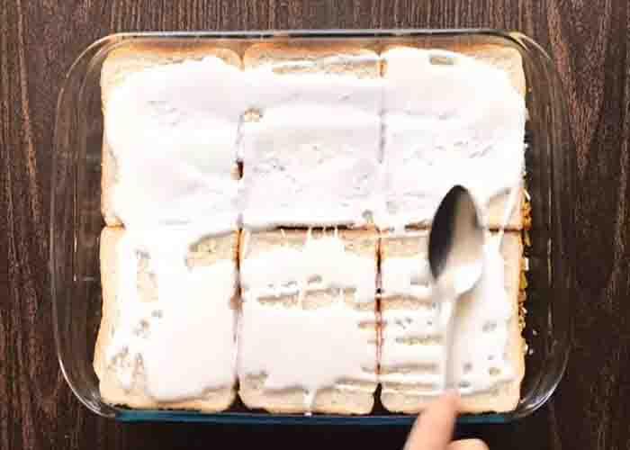 Spreading the cream on top of the bread bake casserole.