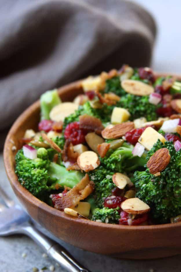 Super healthy broccoli salad with cranberries, sliced almonds and bacon in a dark wooden bowl on grey cloth