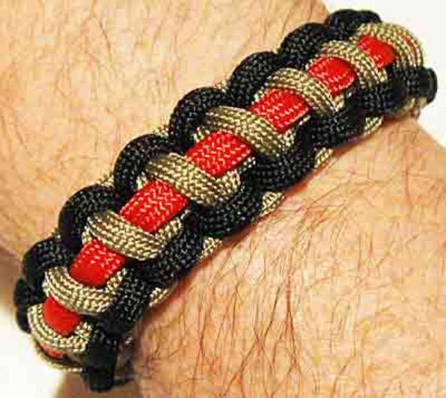 Tri color cobra paracord bracelet in black, tan and red worn on a wrist, showing the rotating stripe pattern