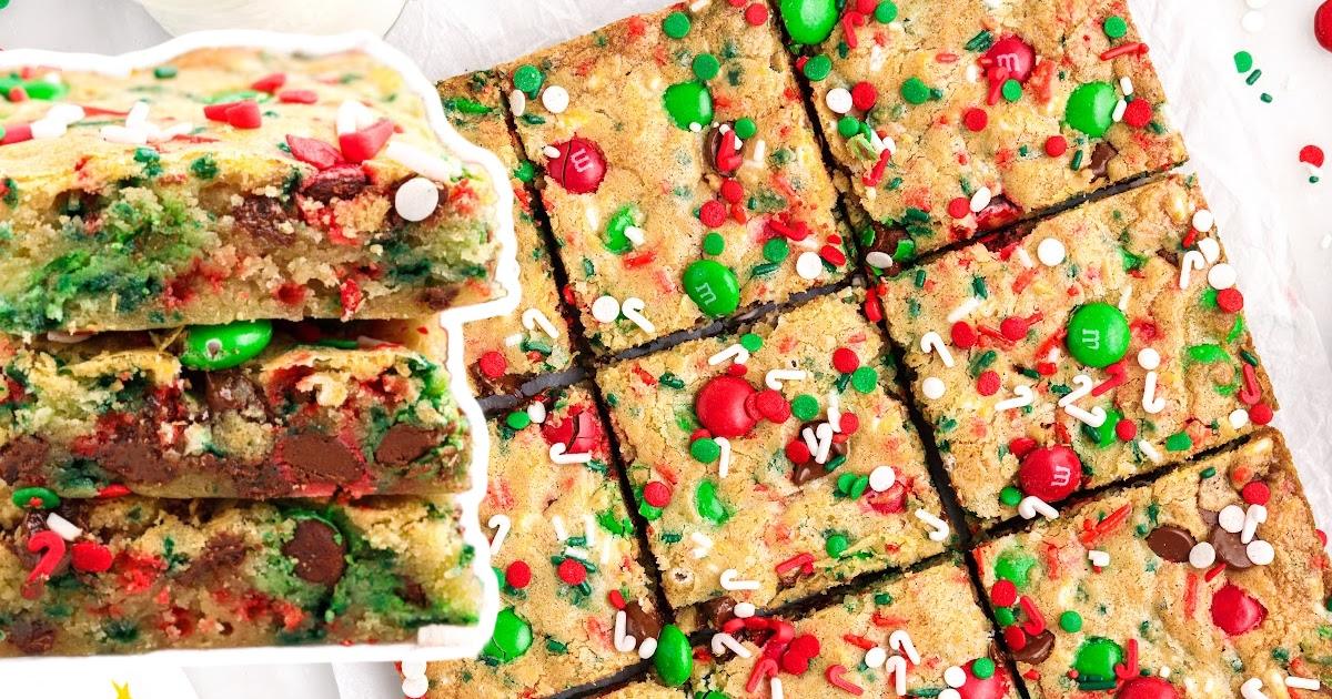 Chewy Christmas cookie bars cut into squares and stacked, full of red and green candies, chocolate chips and sprinkles